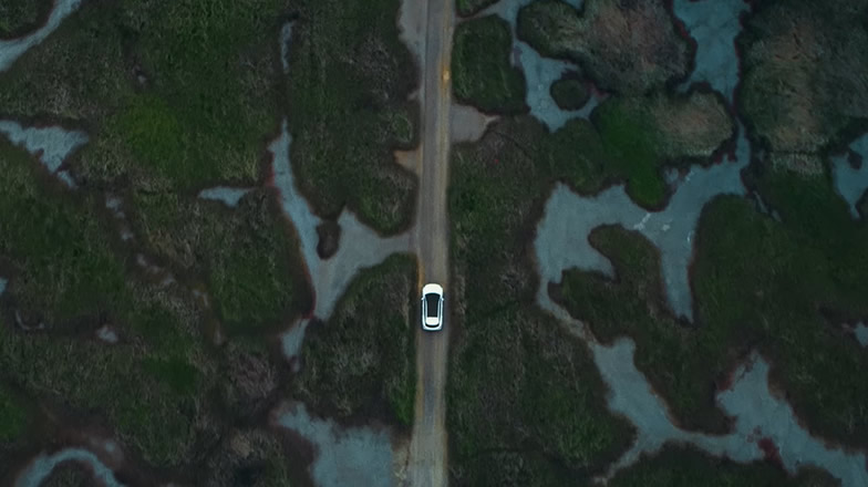 Kia EV6. Driving through landscape. Seen from above.