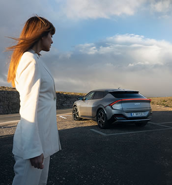Donna in bianco di fronte a Kia EV6